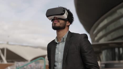 Excited-middle-eastern-man-experiencing-virtual-reality-headset-outdoor